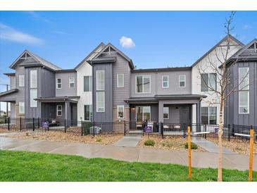 Modern townhouse exteriors with gray siding, large windows, and well-maintained landscaping under a blue sky at 430 Millwall Cir, Castle Pines, CO 80108