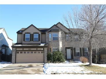Two-story house with beige and brick exterior, attached garage, and landscaping at 18874 E Ida Ave, Aurora, CO 80015