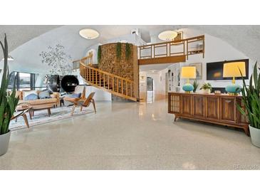 Spacious living room features a unique stone pillar, spiral staircase, and modern furnishings at 6681 S Abilene Way, Centennial, CO 80111