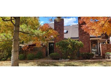 Charming townhome exterior featuring a brick facade with colorful autumn foliage and lush greenery at 11710 Elk Head Range Rd, Littleton, CO 80127