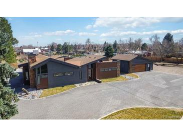 Modern home featuring gray and brown siding with stone accents and a paved driveway at 8900 W Hampden Ave, Denver, CO 80227