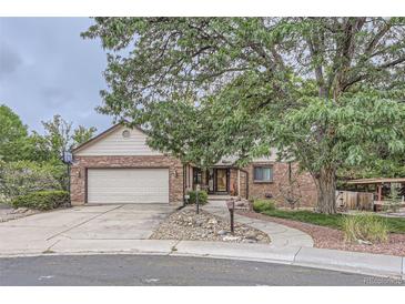 Brick ranch home with attached garage, mature trees, and landscaped yard at 11275 Ranch Pl, Denver, CO 80234