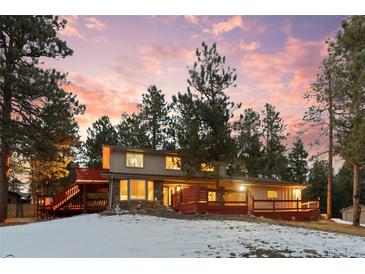 Two-story house with deck, nestled in a wooded area at 28735 Little Big Horn Dr, Evergreen, CO 80439