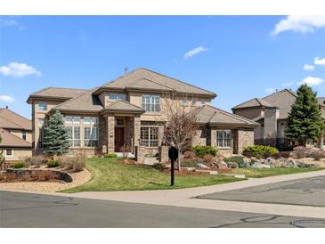 Beautiful two-story home with stone and stucco exterior, tile roof, and professionally landscaped front yard at 9586 Silent Hills Ln, Lone Tree, CO 80124