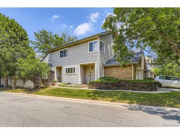 Charming gray two-story townhome showcasing brick accents, mature landscaping, and assigned parking in a desirable community at 2238 S Nome Ct, Aurora, CO 80014