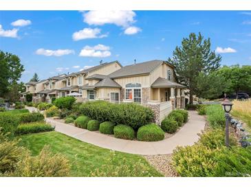 Charming townhome with stone accents, lush landscaping, and inviting walkway on a sunny day at 3795 W 104Th Dr # E, Westminster, CO 80031
