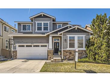Charming gray two-story home with stone accents, a basketball hoop, and a well-manicured lawn at 3024 Woodbriar Dr, Highlands Ranch, CO 80126