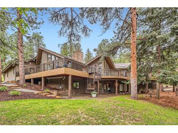 Stunning home featuring a multilevel deck, spiral staircase, manicured lawn, and mature trees at 4856 Cheyenne Dr, Larkspur, CO 80118