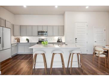 Bright kitchen features gray cabinets, stainless appliances, and an island with seating at 485 Interlocken Blvd # 102, Broomfield, CO 80021
