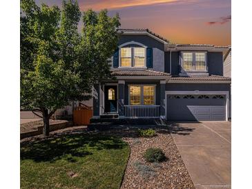 Charming two-story home boasts a covered porch, a well-maintained lawn, and a gray two-car garage at 1963 Hogan Ct, Castle Rock, CO 80109