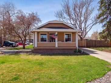Charming home with a well-manicured lawn and cozy front porch showcasing an American flag at 6940 W 48Th Ave, Wheat Ridge, CO 80033