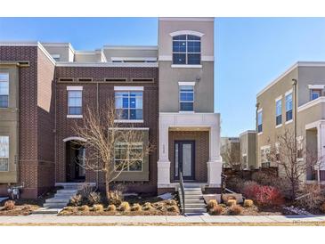 Modern two-story townhome featuring brick and stucco exterior, landscaping, and covered entry at 5438 Valentia St, Denver, CO 80238