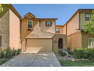 Inviting tan home with a beige two-car garage, an arched entry, and landscaped front yard at 11839 E Maplewood Ave, Greenwood Village, CO 80111