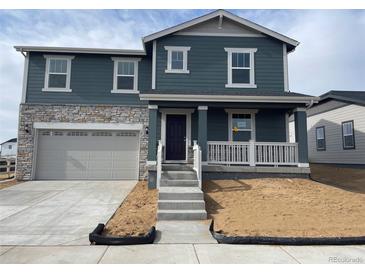 Two-story home with a stone accent wall, attached garage, and a charming front porch with a white railing at 3909 N Shawnee St, Aurora, CO 80019