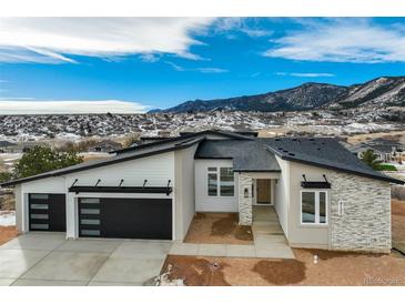 Beautiful modern home showcasing a three car garage and mountain views at 4121 Mesa Top Dr, Monument, CO 80132