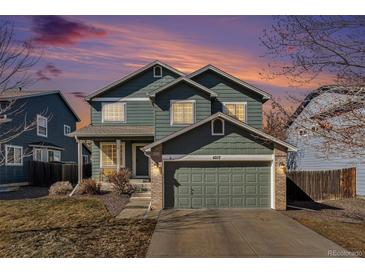 Charming two-story home with a well-manicured lawn and attached two-car garage as the sun sets at 4217 S Jericho St, Aurora, CO 80013