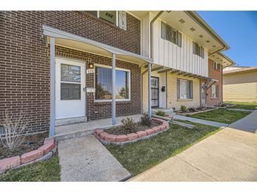 Brick townhouse exterior featuring a covered entry, well-kept lawn, and inviting curb appeal at 610 S Xenon Ct, Lakewood, CO 80228