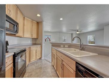 Bright kitchen featuring wood cabinets, tile flooring, and modern appliances at 12833 Mayfair Way # F, Englewood, CO 80112
