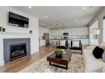 Inviting living room featuring a fireplace, modern decor, and an open floor plan with hardwood floors at 6506 Merrimack Dr, Castle Pines, CO 80108