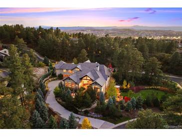 Stunning estate nestled in lush greenery featuring long driveway and mountain views at sunset at 2198 Avenida Del Sol, Castle Rock, CO 80104
