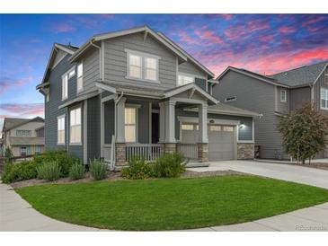 Charming two-story home featuring a covered front porch, well-manicured lawn, and a two-car garage with beautiful landscaping at 12940 Brier Ct, Firestone, CO 80504
