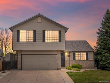 Charming two-story home featuring an attached two-car garage, manicured lawn, and brick accents at 5204 S Parfet Way, Littleton, CO 80127