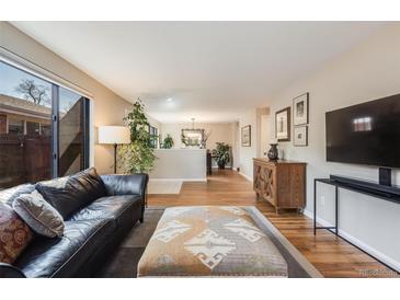 Bright living room features hardwood floors, large window, and comfortable seating area at 1166 Krameria St, Denver, CO 80220