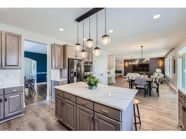 Open kitchen boasts a quartz island, stainless appliances, and modern globe pendant lighting at 7119 S Riviera St, Aurora, CO 80016