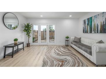 Bright living room with wood floors, white sofa, and glass doors leading to the patio at 2232 Coronado Pkwy # B, Denver, CO 80229