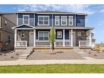 Charming townhome showcasing blue siding, stone accents, and a welcoming front porch with white railings at 9855 Biscay St, Commerce City, CO 80022