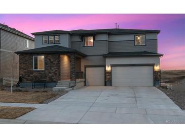 Charming two-story home featuring a stone facade, three-car garage, and a well-manicured front yard at 12663 Buffington Trl, Parker, CO 80134