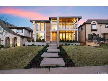 Stunning modern two-story home with large windows, a balcony, a manicured lawn and professional landscaping at 220 Glencoe St, Denver, CO 80220