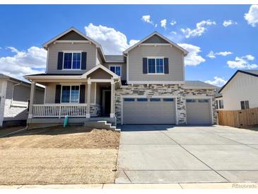 Two-story home featuring a two-car garage, stone accents, gray siding and shutters, and a cozy front porch at 25214 E Warren Pl, Aurora, CO 80018