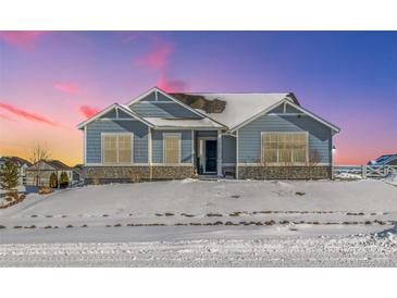 Ranch style home with gray siding, stone accents, and a snowy front yard at 16122 Emporia Way, Brighton, CO 80602