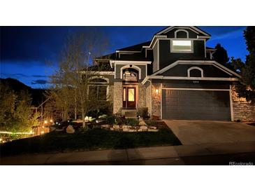 Charming two-story home with a stone facade, manicured lawn, and a two-car garage at twilight at 1312 Pine View Rd, Golden, CO 80403