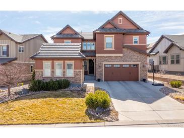 Charming two-story home with stone accents, a well-manicured lawn, and a two-car garage at 1128 Starglow Pl, Highlands Ranch, CO 80126