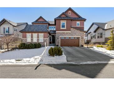 Two-story home with stone and shingle accents, attached garage, and snow-covered landscaping at 1128 Starglow Pl, Highlands Ranch, CO 80126