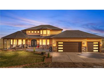 Stunning two-story home boasts a manicured lawn and an attached three-car garage with stone accents at 942 S County Road 129 Rd, Bennett, CO 80102