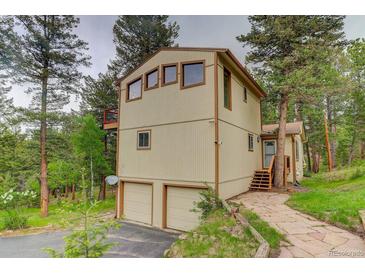 Tan two-story home with a two car garage, wood trim, and a stone walkway at 9209 William Cody Dr, Evergreen, CO 80439