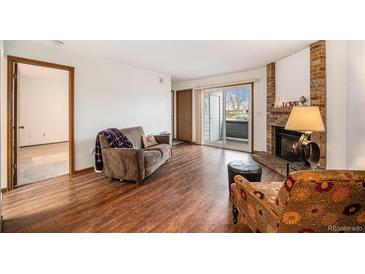 Cozy living room features a brick fireplace, wood floors, and sliding door to balcony at 8025 W Eastman Pl # 2-102, Lakewood, CO 80227