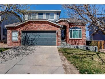 Charming brick home featuring a two-car garage and a well-maintained front yard at 10486 Cheetah Winds, Lone Tree, CO 80124