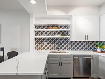 Modern kitchen features updated appliances, grey and white cabinets, quartz countertops, and decorative tile backsplash at 345 Fillmore # 407, Denver, CO 80206