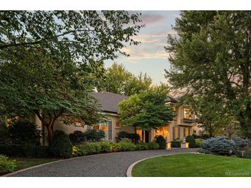 Elegant home featuring lush landscaping, a circular driveway, and warm exterior lighting at 1350 E Greenwood Ln, Greenwood Village, CO 80121