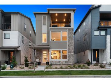 Contemporary three-story home featuring stone accents, a private balcony, and well-maintained landscaping at 12270 W 57Th Ave, Arvada, CO 80002