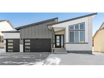 Modern two-story home with a gray exterior, black garage door, and snow-covered yard at 16840 Mckay Dr, Mead, CO 80542