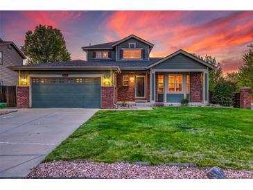 Charming two-story home with manicured lawn and a two-car garage, set against a stunning sunset backdrop at 2587 S Flanders Ct, Aurora, CO 80013