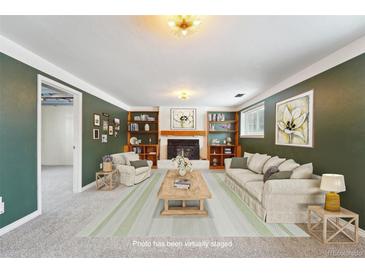 This bright living room boasts a fireplace with built-in bookshelves and a large window at 15895 E 17Th Pl, Aurora, CO 80011