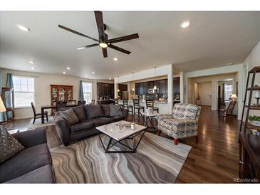 Spacious living room with a modern ceiling fan, plush seating, and an open floor plan leading to the kitchen at 848 Sandstone Cir, Erie, CO 80516
