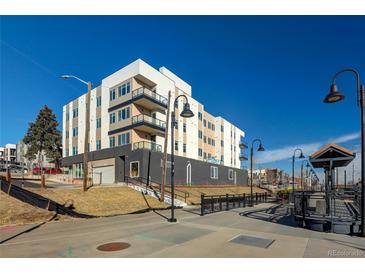 Modern apartment building with white and gray facade, balconies, and walkway to the train station at 1208 Quitman St # 202, Denver, CO 80204