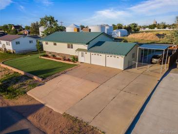 Two-story home with green roof, large driveway, and fenced carport on sunny day at 470 Mcdonnell St, Byers, CO 80103